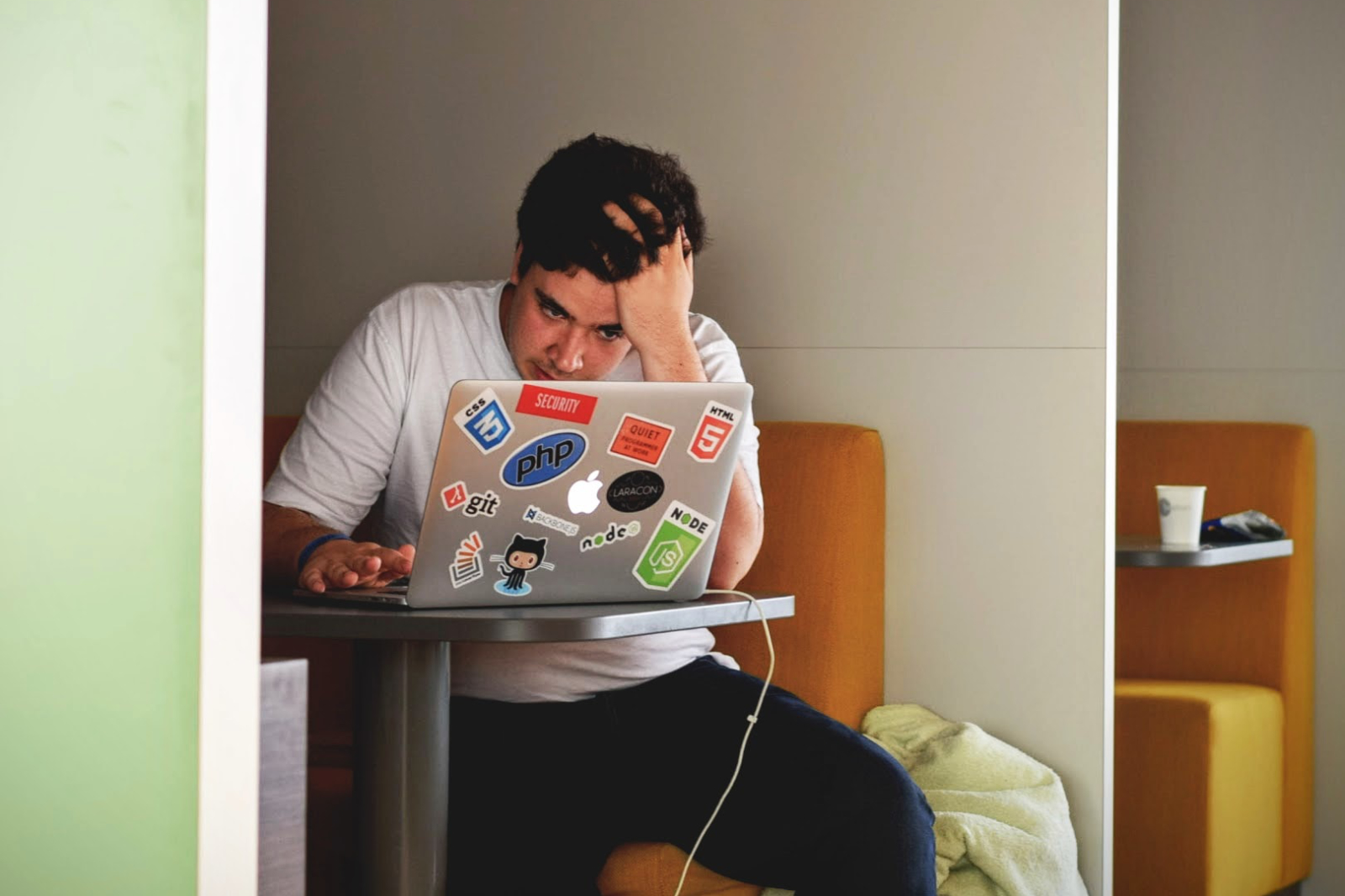 Mann som sitter foran laptop med hånden i pannen